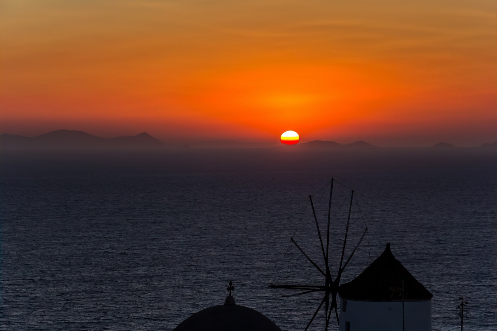 The sun setting over the whitewashed clifftop houses of Oia, Santorini